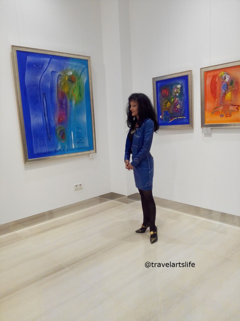 The artist posing in front of her colourful works of art